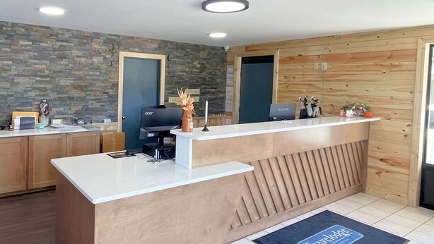 A reception desk with a stone wall backdrop, wooden paneling, and a tiled floor.