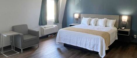 A hotel room with a large bed, bedside tables, a chair, and a window with curtains.