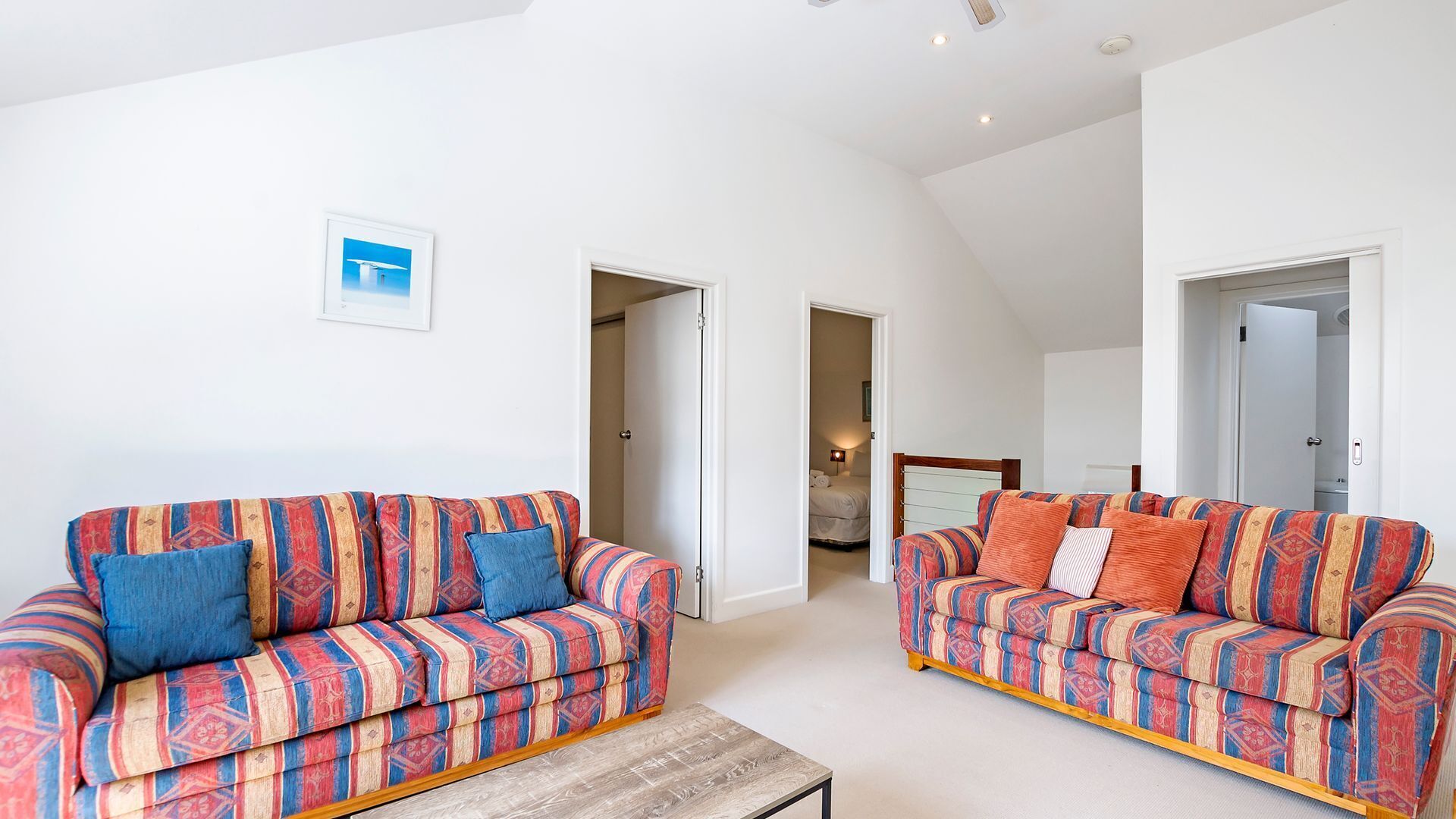 A spacious living area with two patterned sofas and a wooden coffee table.