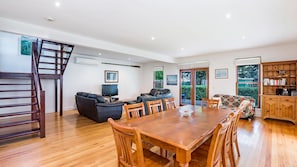 A spacious living area with a wooden dining table, sofas, and a TV. - Ideal family home a just a stones through from the popular Little East Beach (Port Fairy)