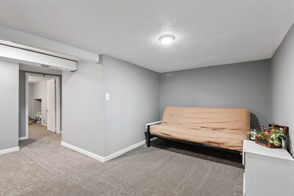 A room with a beige sofa, a white cabinet, and a small plant on the right side.