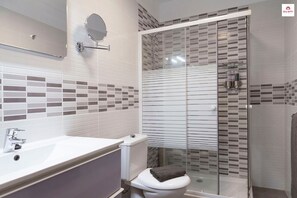A modern bathroom with a white sink, toilet, and shower enclosure.