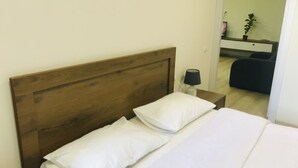 Una cama bien tendida con ropa blanca en una habitación con cabecera de madera.
