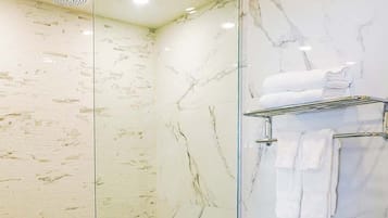 A bathroom with a glass-enclosed shower, a toilet, and a sink.