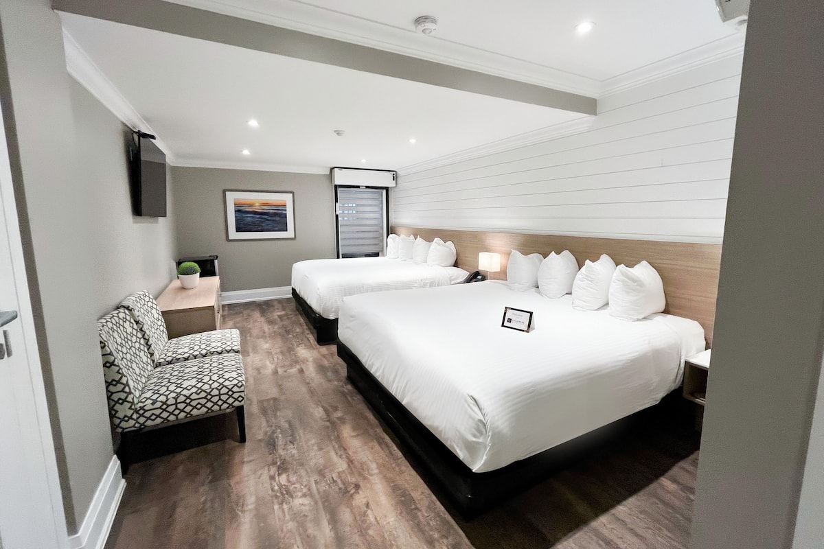 Une chambre d’hôtel avec deux lits, un bureau, une chaise et une télévision.