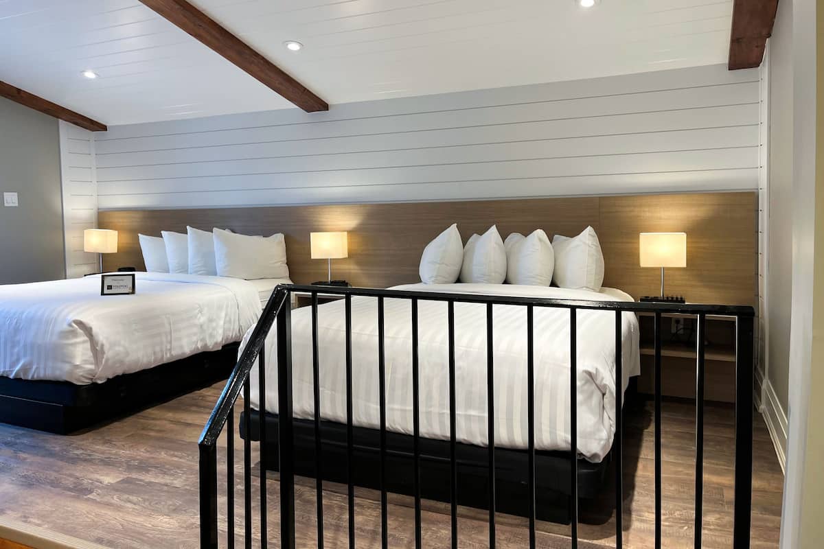 Une chambre d’hôtel avec deux lits, des têtes de lit en bois et des lampes de chevet.