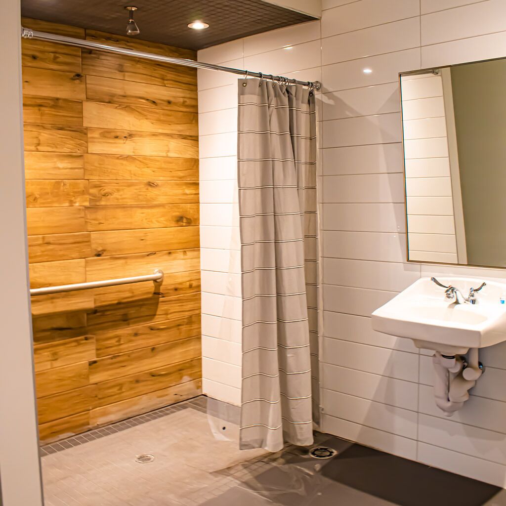 A bathroom with a wooden wall, a shower curtain, a sink, and a mirror.
