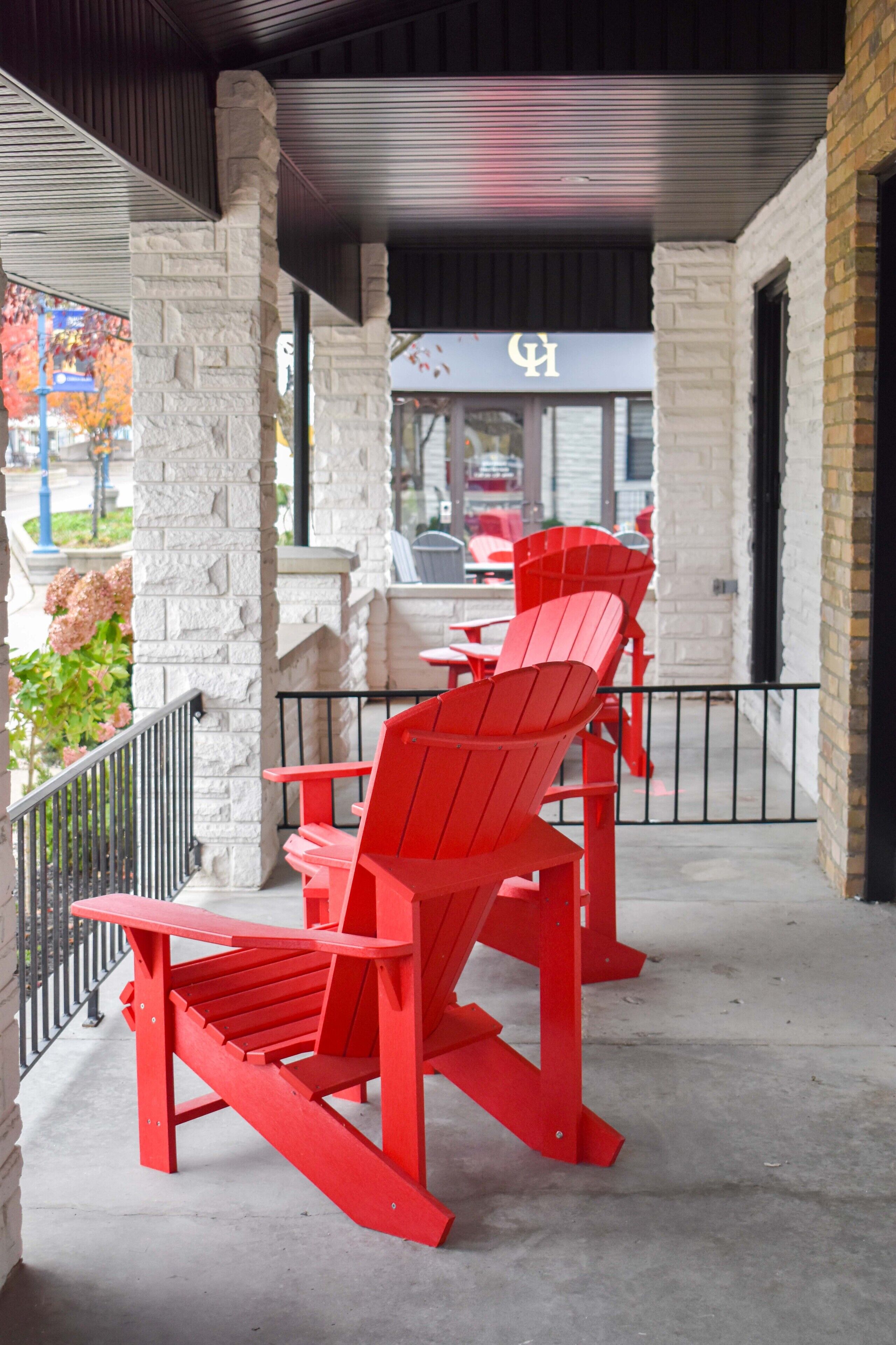 Un espace extérieur abrité, aménagé avec des chaises Adirondack rouges et un mur en pierre.