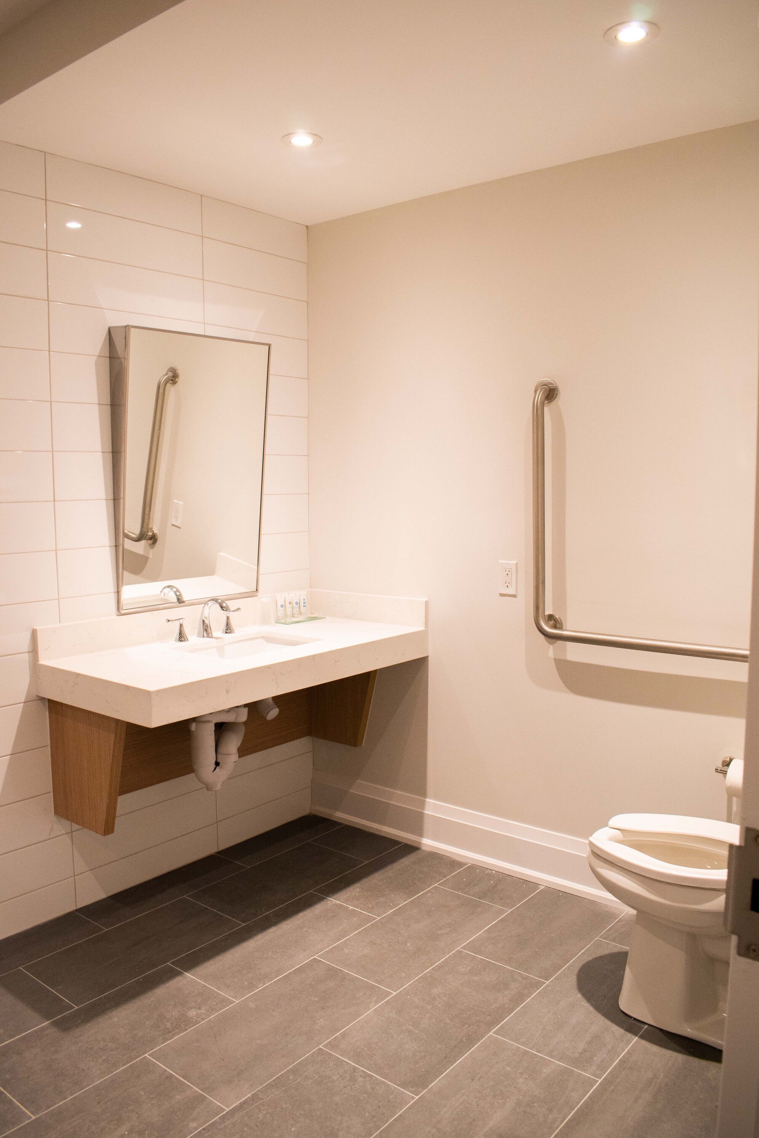 A modern bathroom with a white sink, mirror, and toilet.