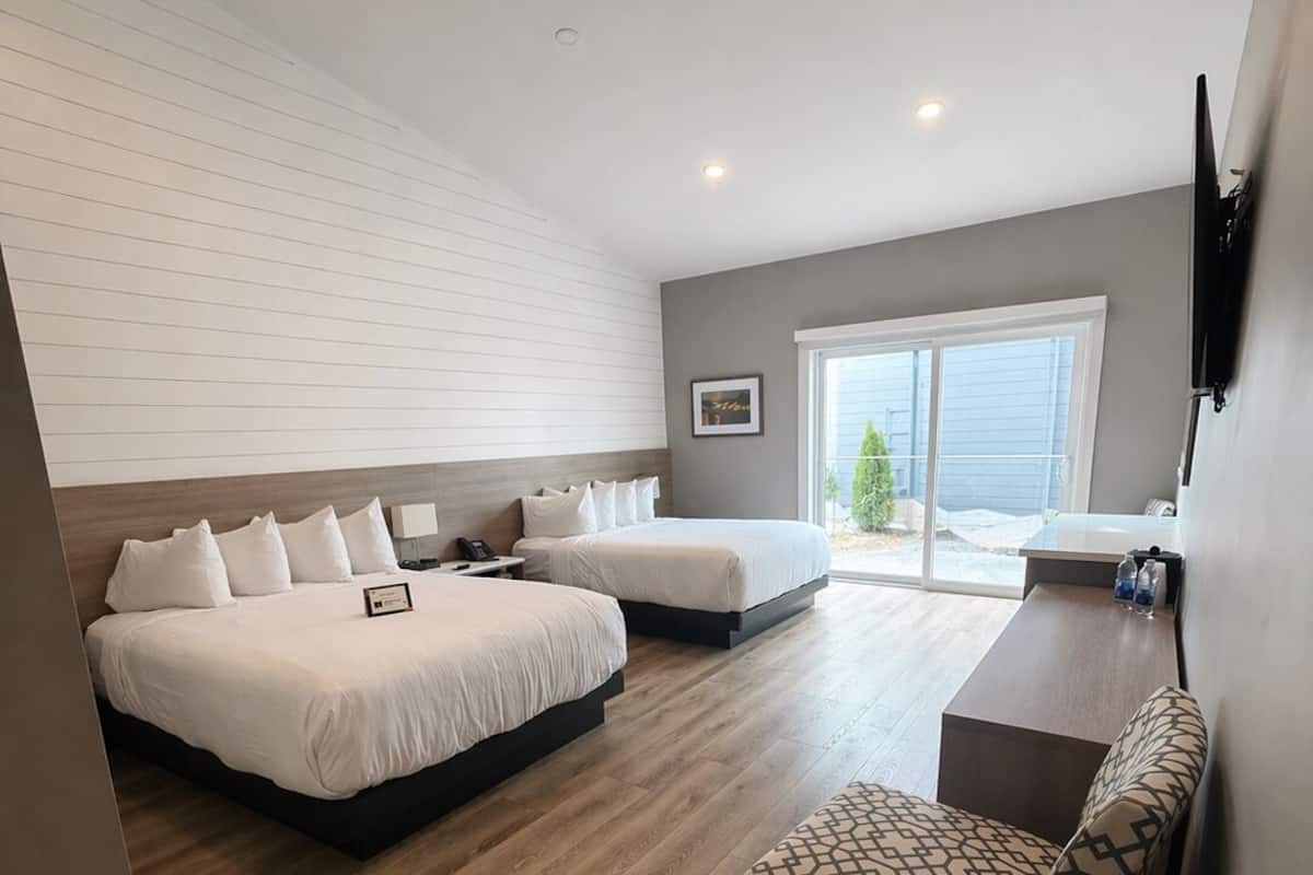 Une chambre d’hôtel moderne avec deux lits, un coin salon et une grande fenêtre.