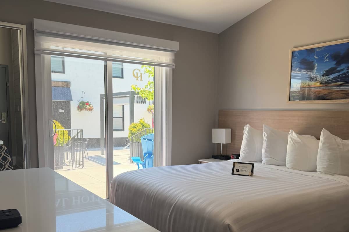Une chambre d’hôtel avec un grand lit, un bureau, une chaise et une vue sur l’extérieur.