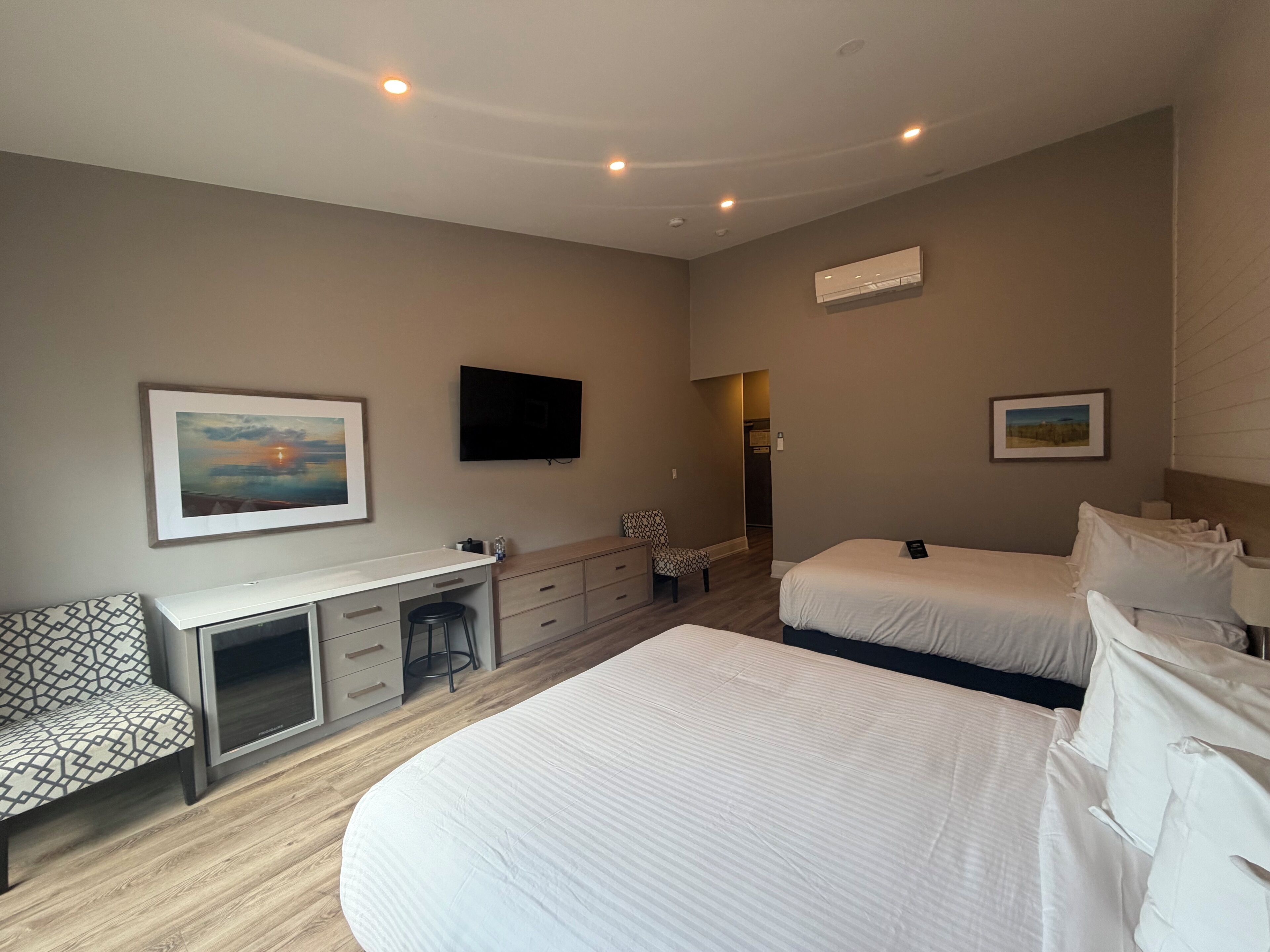 Une chambre d’hôtel équipée d’un lit, d’un bureau, d’une chaise, d’une télévision et décorée avec des œuvres d’art.