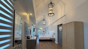 A hotel room with a bed, bedside tables, a wardrobe, a desk, and a chair. - Colonial Hotel & Suites  (Lambton Shores)