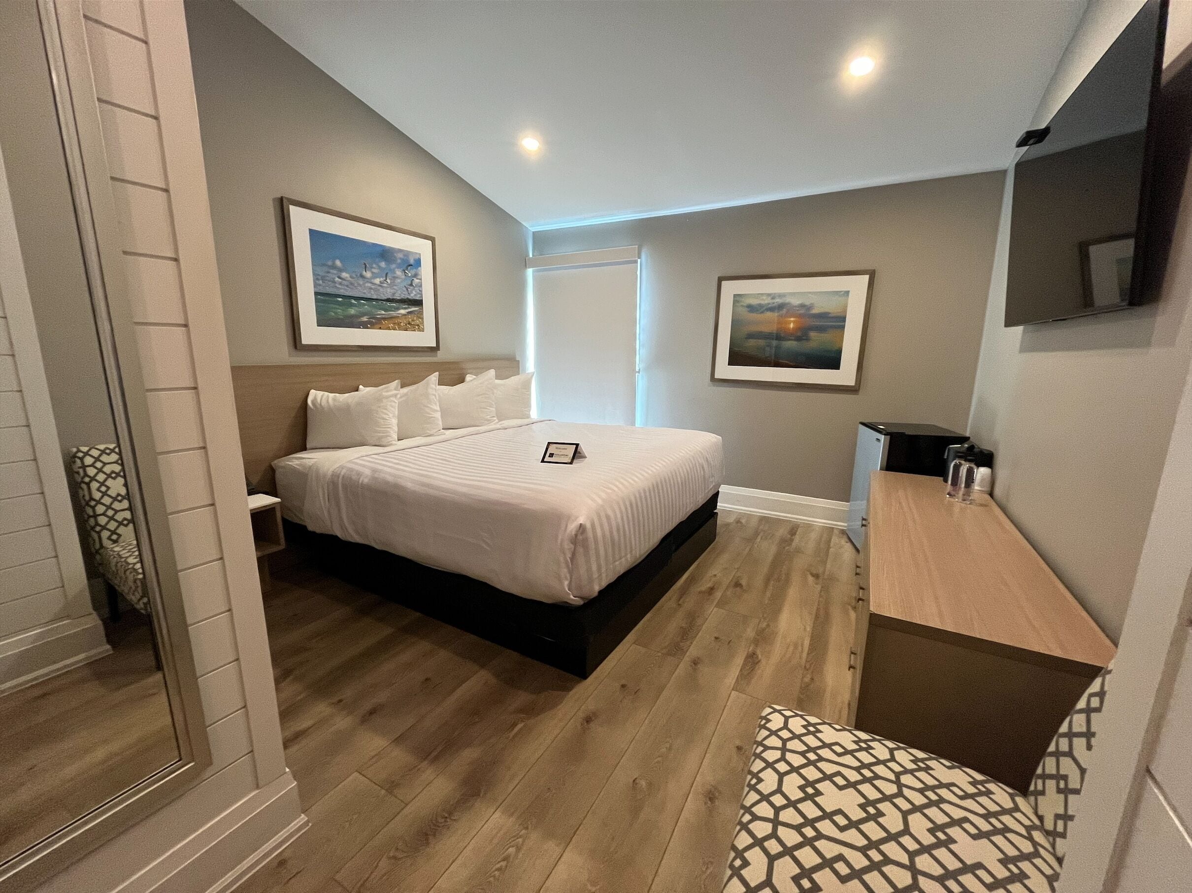 Quarto com cama, mesa de cabeceira e escrivaninha com cadeira.