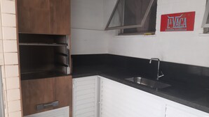 Une cuisine dotée d’un plan de travail noir, d’un évier en acier inoxydable et de meubles de rangement en bois.