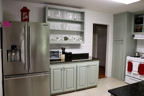 Uma cozinha com geladeira de aço inoxidável, forno embutido e bancada com torradeira e cafeteira.