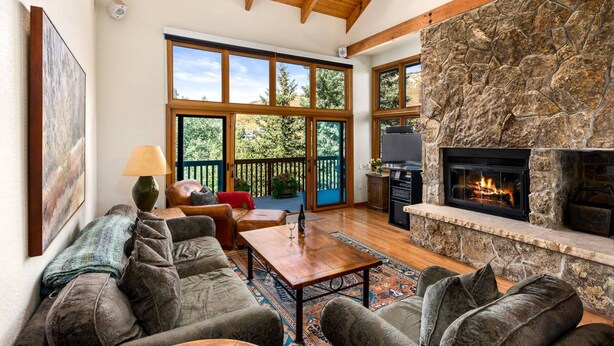 Un salón espacioso con chimenea de piedra, ventanas amplias y una zona de estar acogedora.