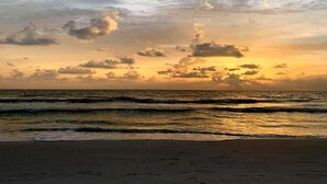 Une plage avec des vagues et un coucher de soleil.