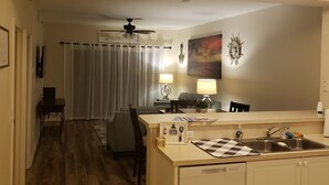 Une cuisine compacte dotée d’un évier intégré, d’un coin repas avec une table et des chaises, et d’un ventilateur de plafond.