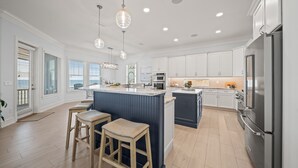A modern kitchen with a central island, stainless steel appliances, and pendant lighting. - Spectacular Ocean Front home (Flagler Beach)
