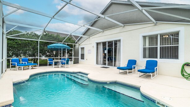 A covered swimming pool with blue chairs and a blue umbrella. - Elegant 4BR Villa w/ Private Pool & Spa near Disney - Backs Onto Conservation! (Davenport)