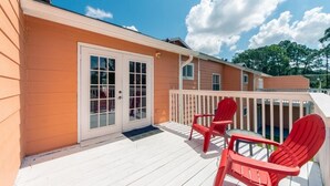 Une terrasse en bois avec des chaises rouges et une balustrade blanche.