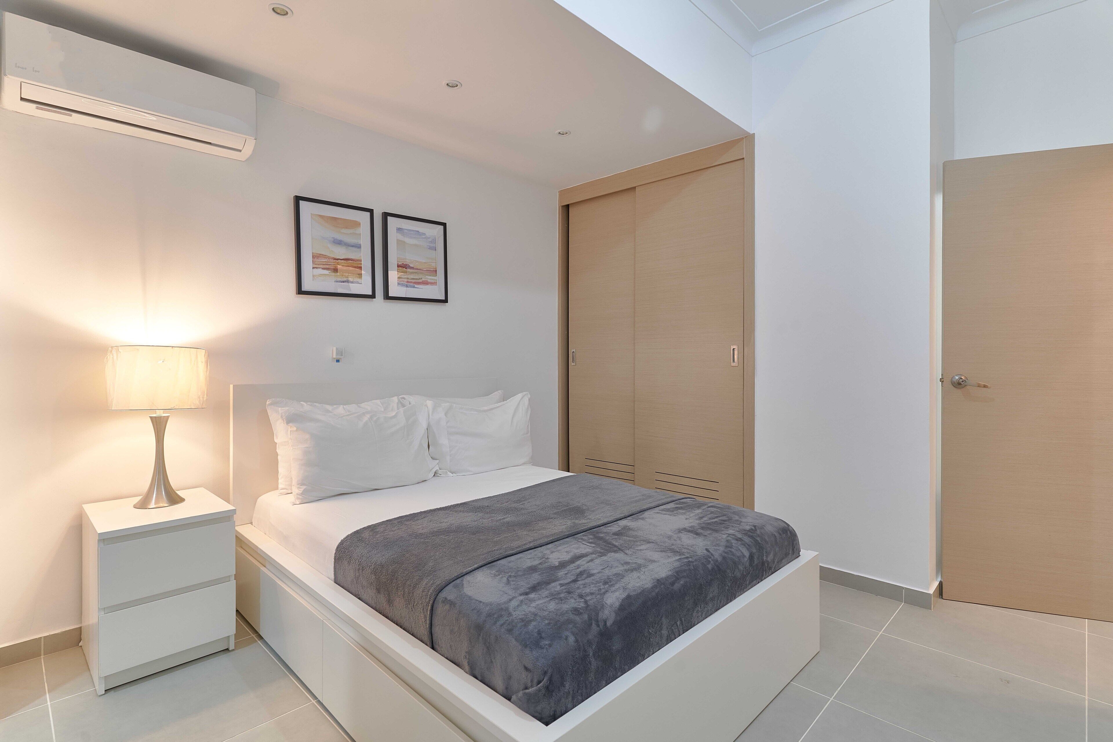 Een moderne slaapkamer met een bed, nachtkastje en een kledingkast.