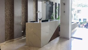 Un espace d’accueil moderne avec un comptoir en marbre, des luminaires suspendus et un pot d’orchidée.