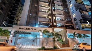 Un hôtel moderne doté d’une façade en verre, de nombreux balcons et d’une entrée bien éclairée.