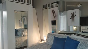 Quarto com cama, mesa de cabeceira, espelho e guarda-roupa.