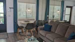Uma sala de estar com um sofá marrom, uma mesa de centro e um espaço de refeições com mesa e cadeiras.
