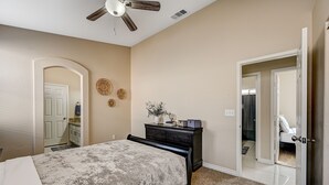 A bedroom with a bed, dresser, ceiling fan, and a door leading to another room. - Clean, Convenient & Comfortable Vegas House (Las Vegas)