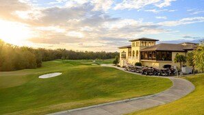 Un parcours de golf doté d’un club-house, d’une pelouse bien entretenue et d’un ciel dégagé.