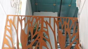 A wooden decorative partition with a tree-like design, a ceiling with exposed pipes and a light fixture, and a white wall with a door. - Treat yourself to Luxury (Delta)