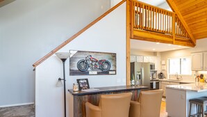 A kitchen with a wooden island, bar stools, and a motorcycle painting on the wall.