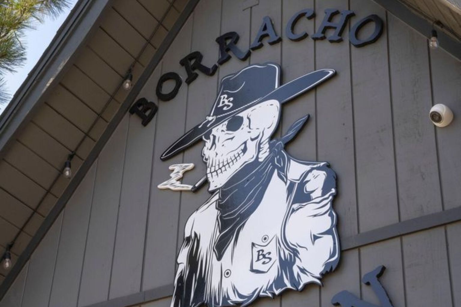 A building with a sign that reads "BORRACHO" and a graphic of a skull wearing a hat.
