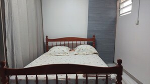 Ein Einzelbett mit Holzrahmen und einer weißen Matratze mit Blumenmuster.