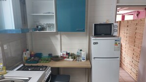 Eine kompakte Küche mit Herd, Spüle, Mikrowelle und Kühlschrank.
