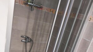 Eine Duschkabine mit gefliestem Boden und Duschkopf.