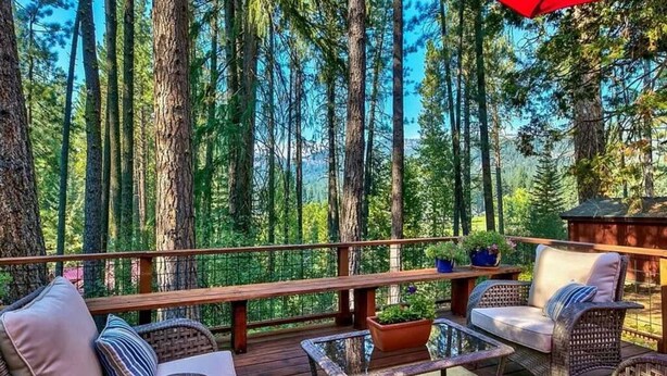 Una terraza con mobiliario de mimbre, una mesa de vidrio y plantas en macetas.