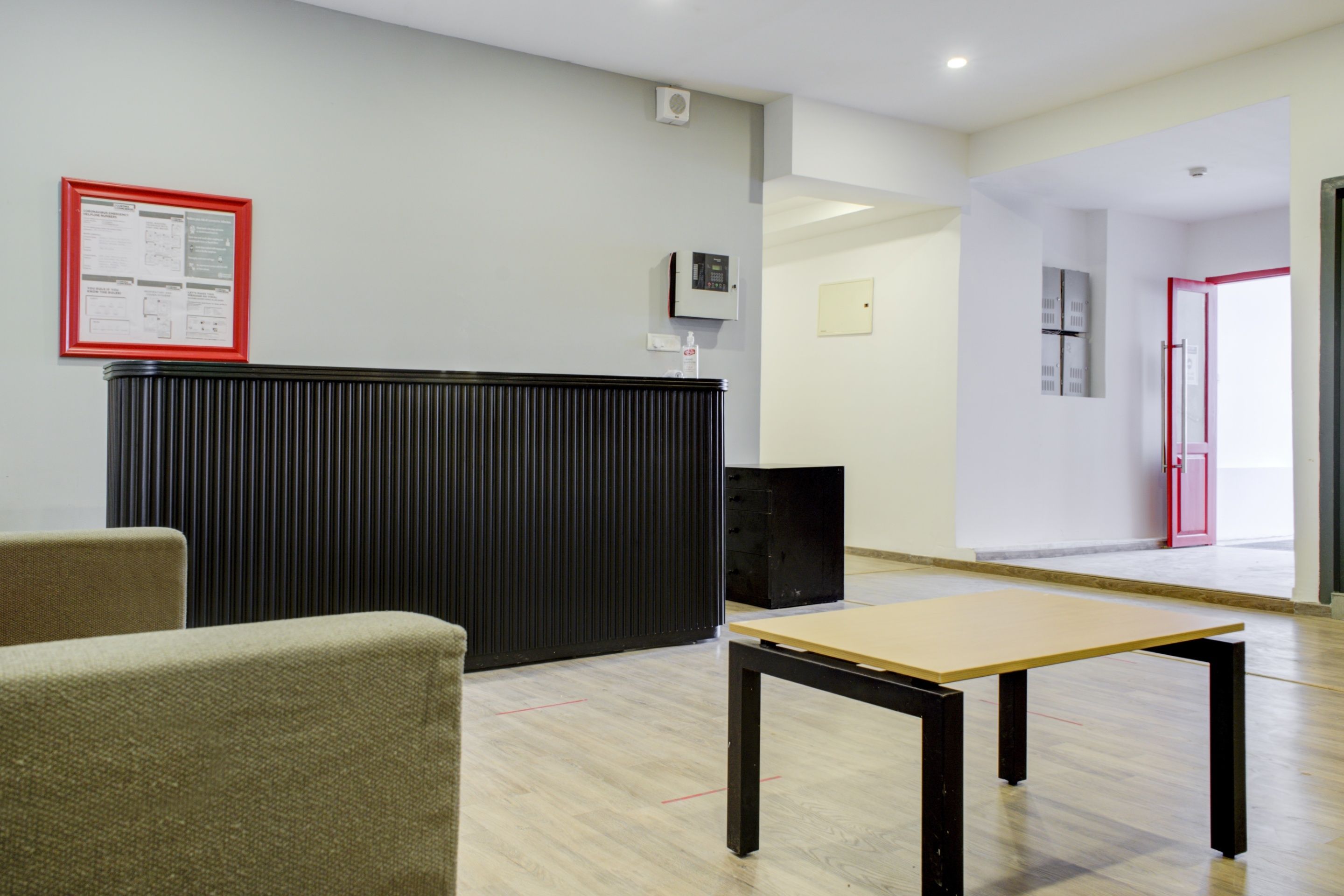 A reception area with a black counter, a framed notice, a small table, and a door leading to another room.