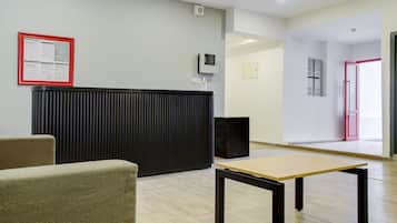 A reception area with a black counter, a framed notice, a small table, and a door leading to another room.