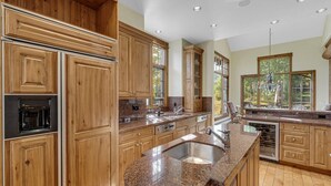 A kitchen with wooden cabinets, granite countertops, a built-in oven, and a large window.