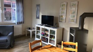 Ein Wohnzimmer mit Fernseher, Bücherregalen, Kamin und Essbereich.