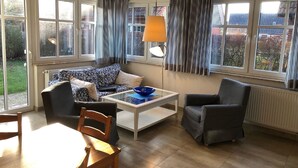 Ein Wohnzimmer mit einer Couch, Sesseln, einem Couchtisch und einem Esstisch.
