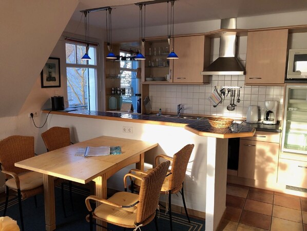 A kitchen with a wooden table and chairs, a built-in oven, and a coffee maker.