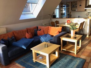 A cozy living room with a sofa, two coffee tables, and a dining area with a table and chairs.
