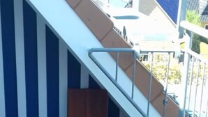 A wooden deck with a metal railing, a staircase, and a blue and white striped wall. - Stromstrasse 2 Whg. 26 "Boddenblick" - maisonette apartment in Mediterranean style (Zingst)