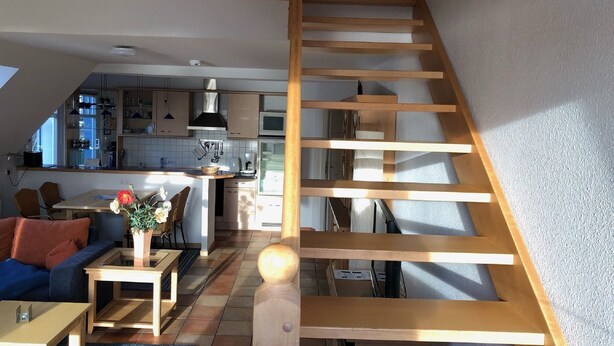 A modern loft apartment with a wooden staircase, a kitchen with white cabinets, and a living area with a sofa and coffee table. - Stromstrasse 2 Whg. 26 "Boddenblick" - maisonette apartment in Mediterranean style (Zingst)