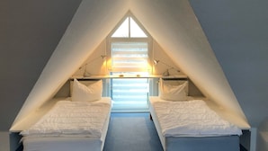 A small, triangular attic bedroom with two single beds, a skylight, and a radiator. - Stromstrasse 2 Whg. 26 "Boddenblick" - maisonette apartment in Mediterranean style (Zingst)